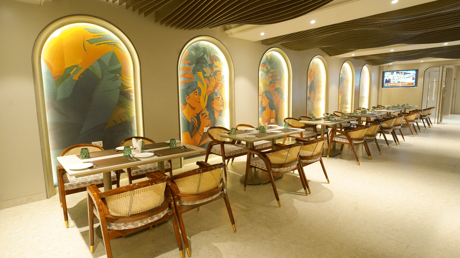 Long restaurant seating area with tables aligned beside arched mural walls at Nirvana Gateway.