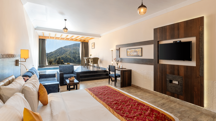 A bedroom with made bed, patterned runner and a tv mounted on the wall under a warm lighting -  Via Lakhela Resort & Spa