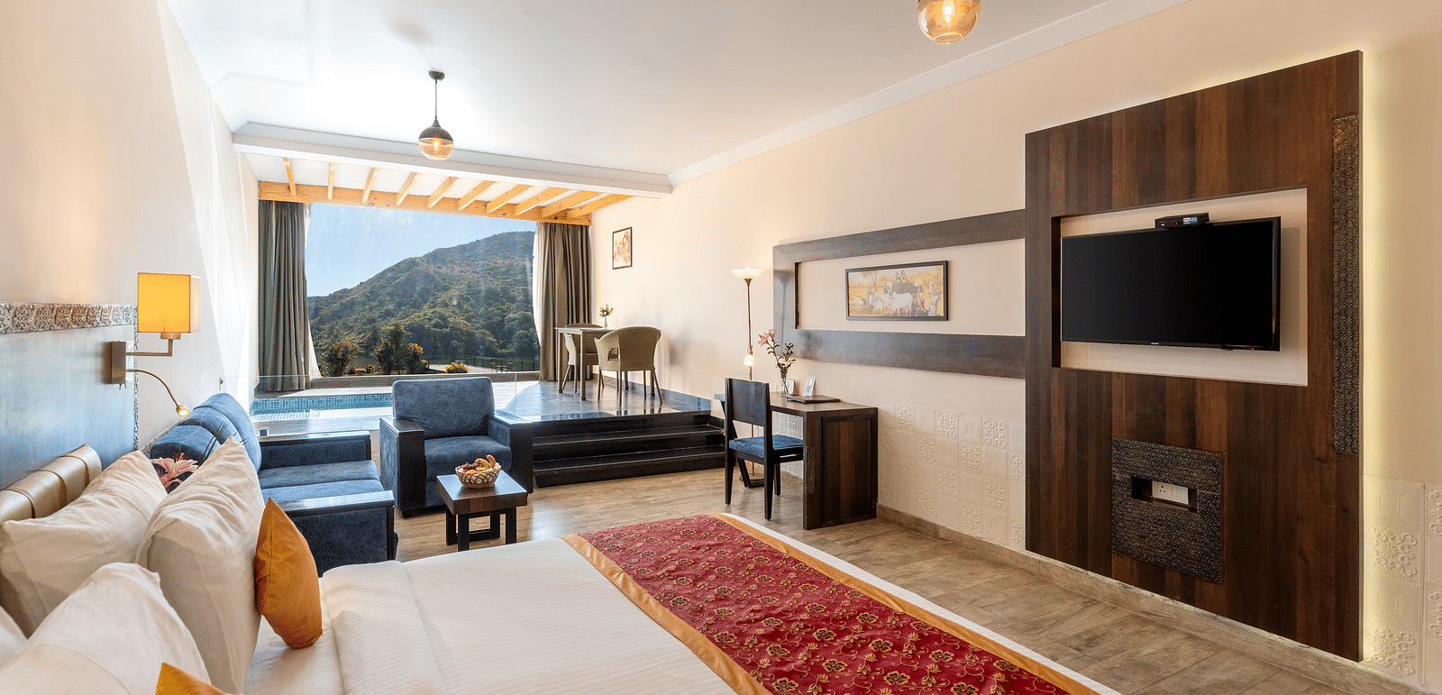 A bedroom with made bed, patterned runner and a tv mounted on the wall under a warm lighting -  Via Lakhela Resort & Spa