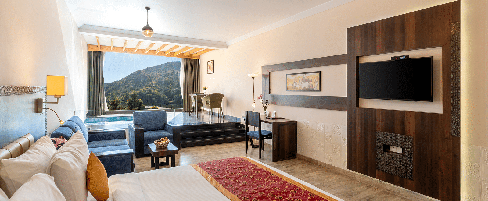 A bedroom with made bed, patterned runner and a tv mounted on the wall under a warm lighting -  Via Lakhela Resort & Spa