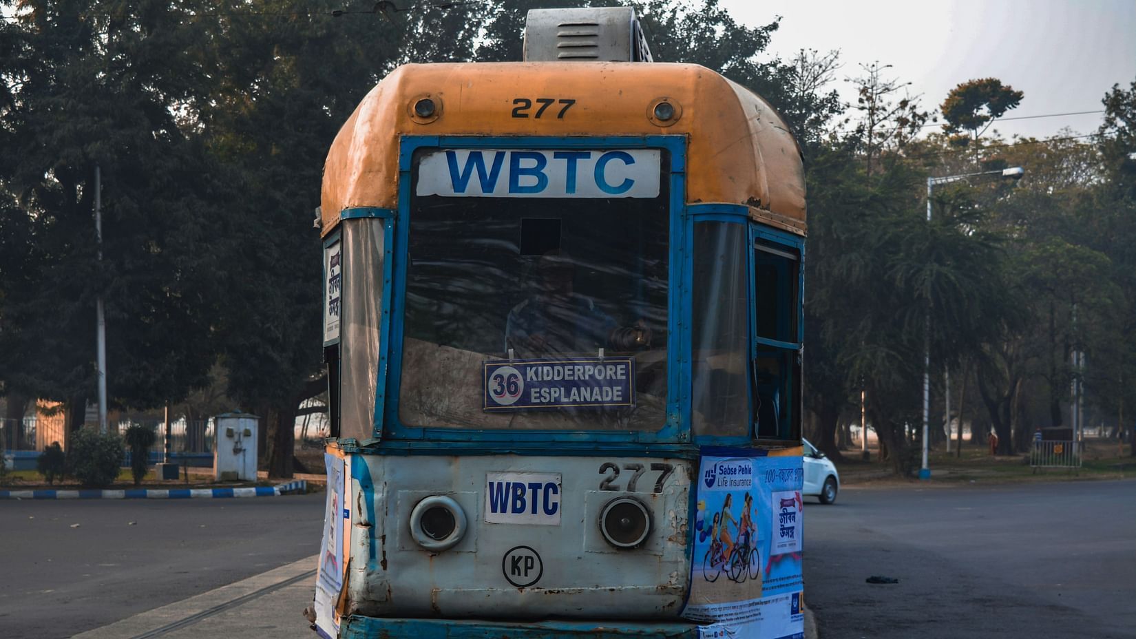 an overview of a yellow coloured tram in kolkata on the road