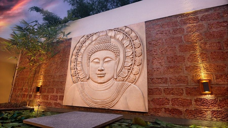 Artistic Buddha wall sculpture with ambient lighting in an outdoor setting.