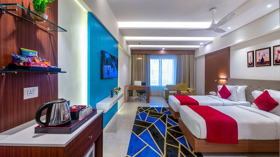 Room interior with double bed, TV, minibar, and access to a balcony area - Lords Eco Inn Shapar Rajkot
