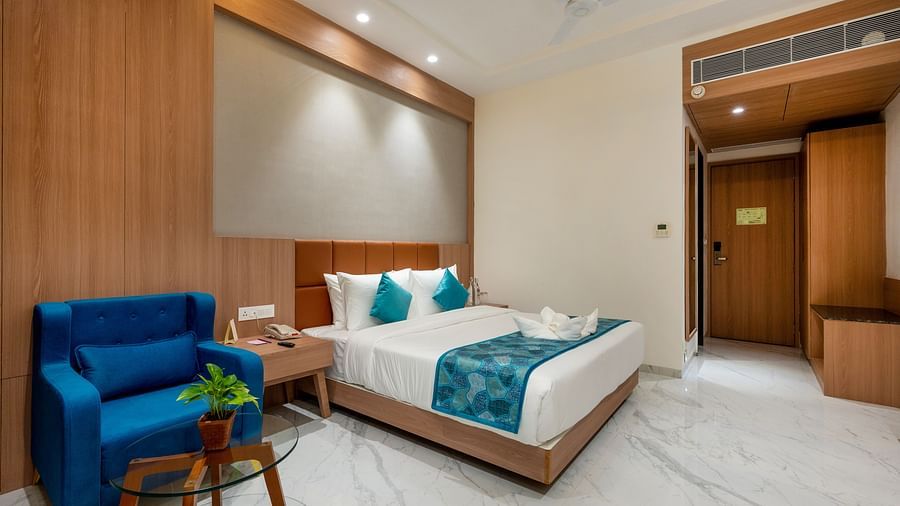 a double bed with blue runner inside one of the Rooms - The Orchid Hotel, Jamnagar