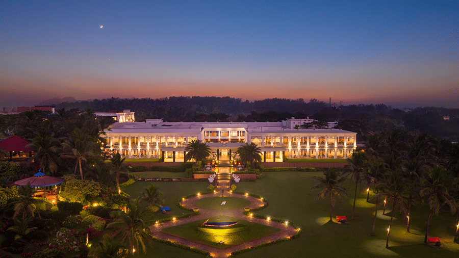 Illuminated grand building of MAYFAIR Palm Beach Resort, Gopalpur-on-Sea set amidst expansive landscaped gardens at dusk.