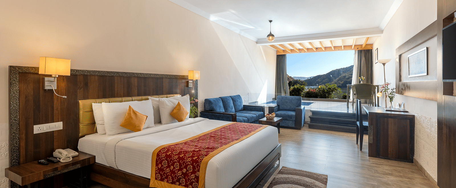 A bedroom neatly arranged with a made bed, a patterned runner on it and a lamp on the ceiling - Via Lakhela Resort & Spa