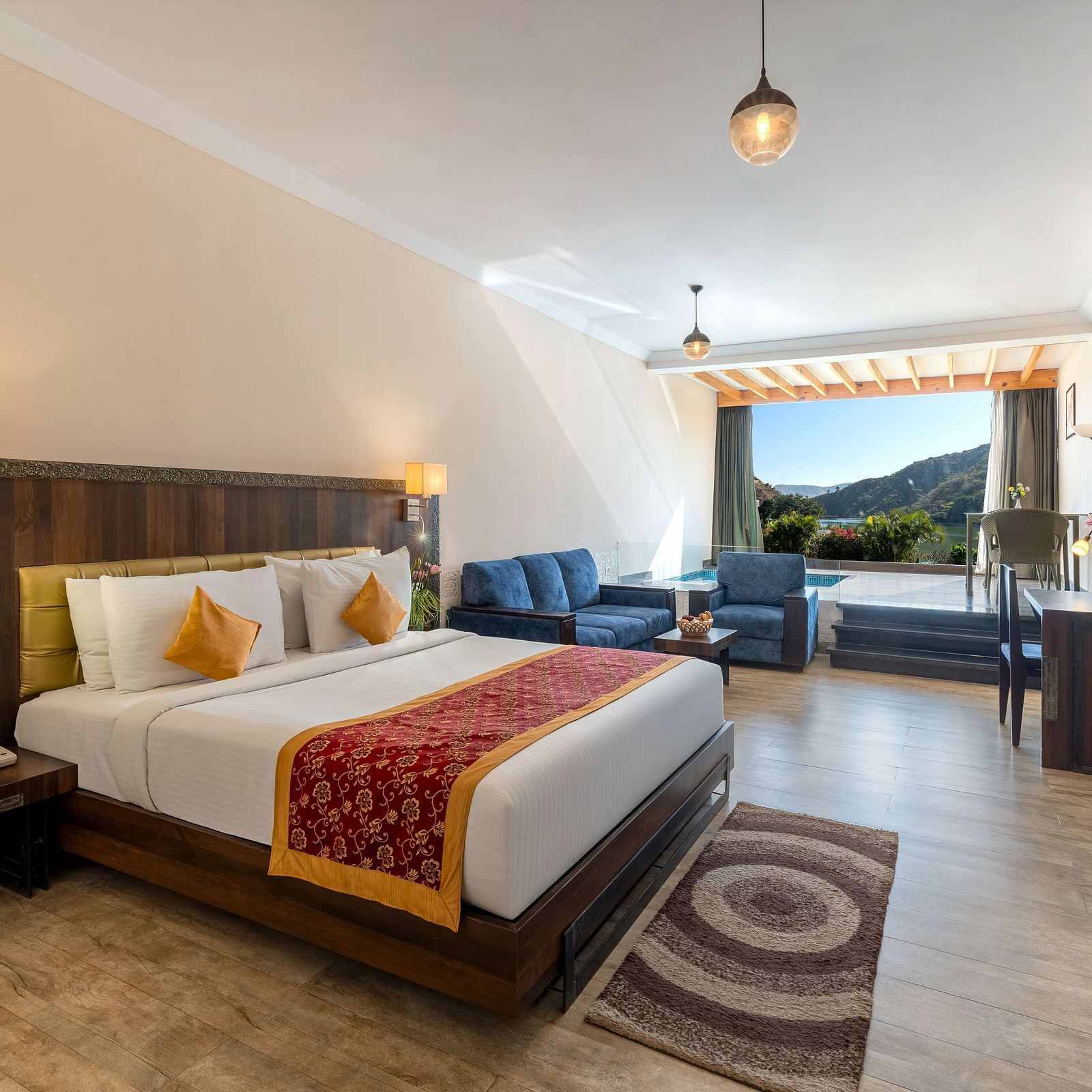 A bedroom neatly arranged with a made bed, a patterned runner on it and a lamp on the ceiling - Via Lakhela Resort & Spa