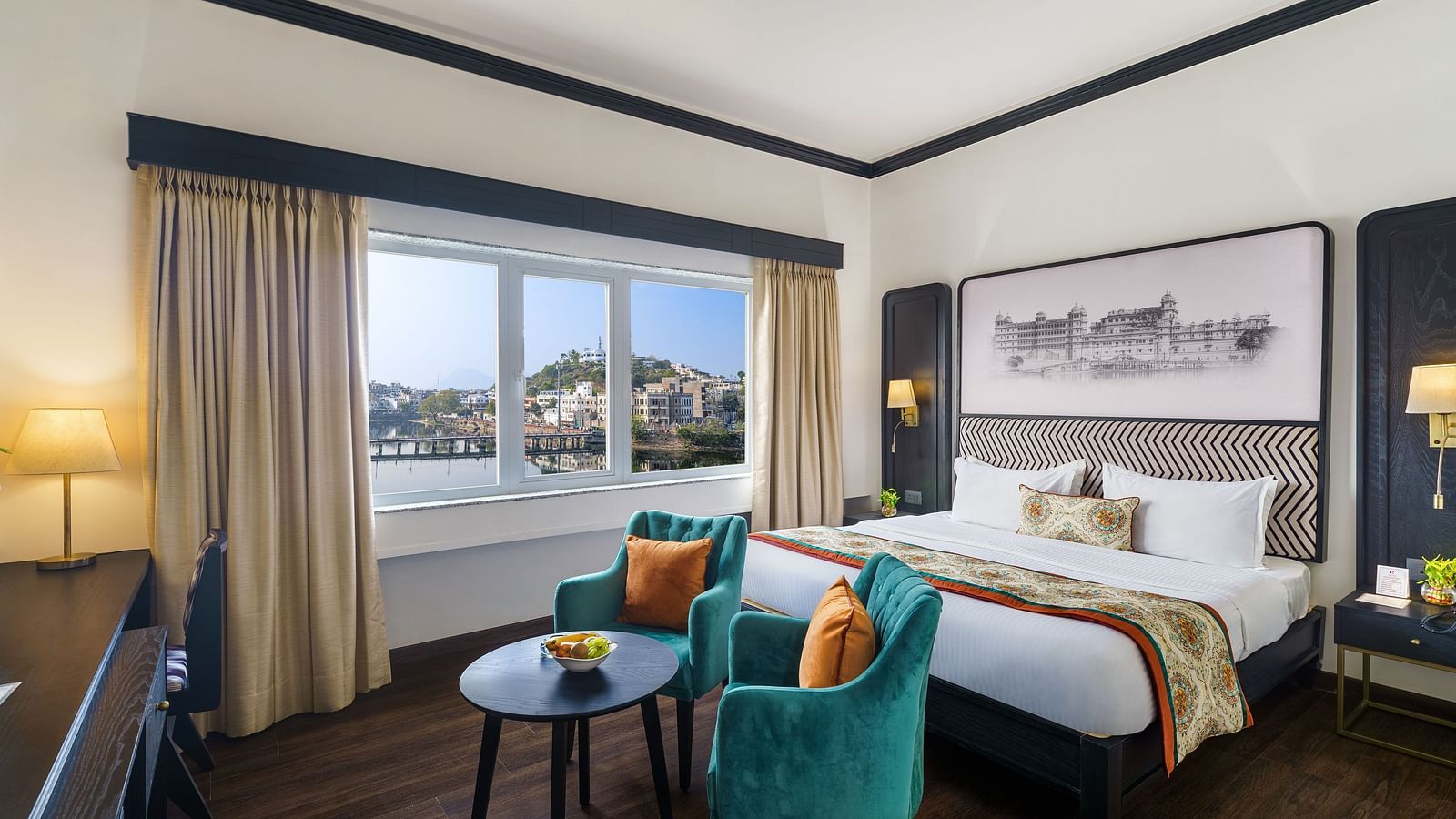 An overview of the superior room with a double bed and chairs in front of it - Hotel Rajdarshan, Udaipur.