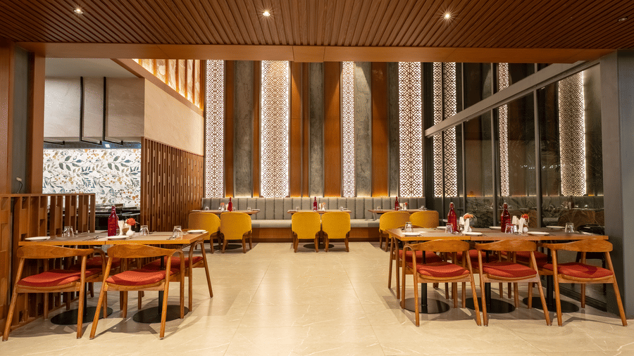 A Wyndham Garden dining area with light flooring, wooden tables, standard and booth-style seating, and decorative vertical wall panels.
