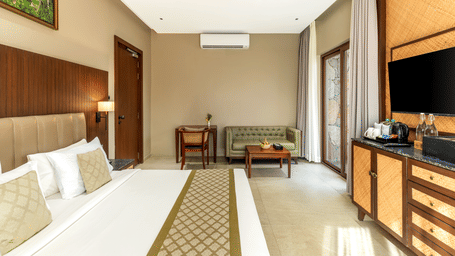 A well-appointed hotel suite features a comfortable bed, ceiling fan, and a flat-screen television unit - Sajjan Bagh Resort and Spa, Kumbhalgarh