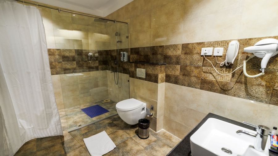 Washroom at Inde Reva Resorts Rishhikesh featuring a shower area with curtain, toilet and a vanity.