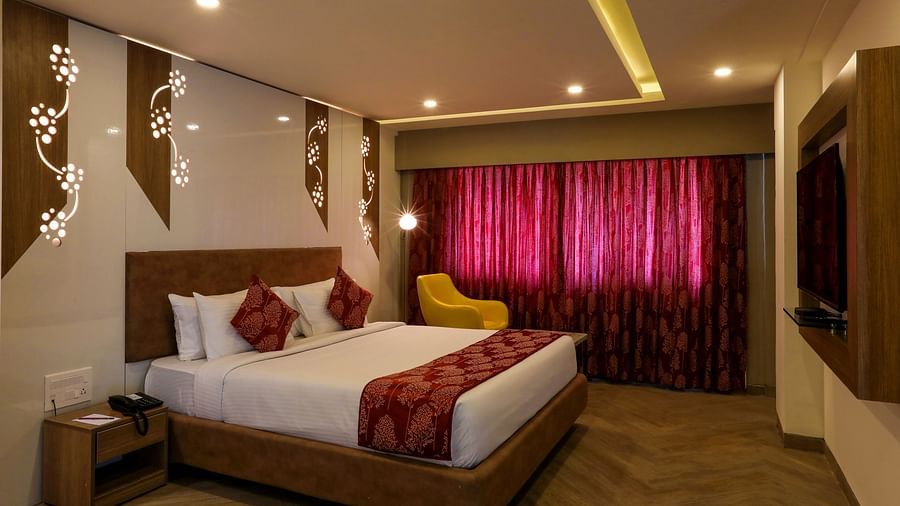 A bedroom with a large bed placed in the middle facing a mounted television - Mango Hill Central, Chennai