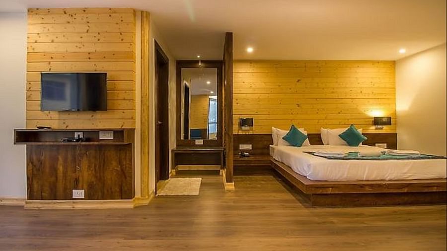 An image of a deluxe suite with a bed, flat screen TV, and a full length mirror - Yashshree Sanderling, Darjeeling