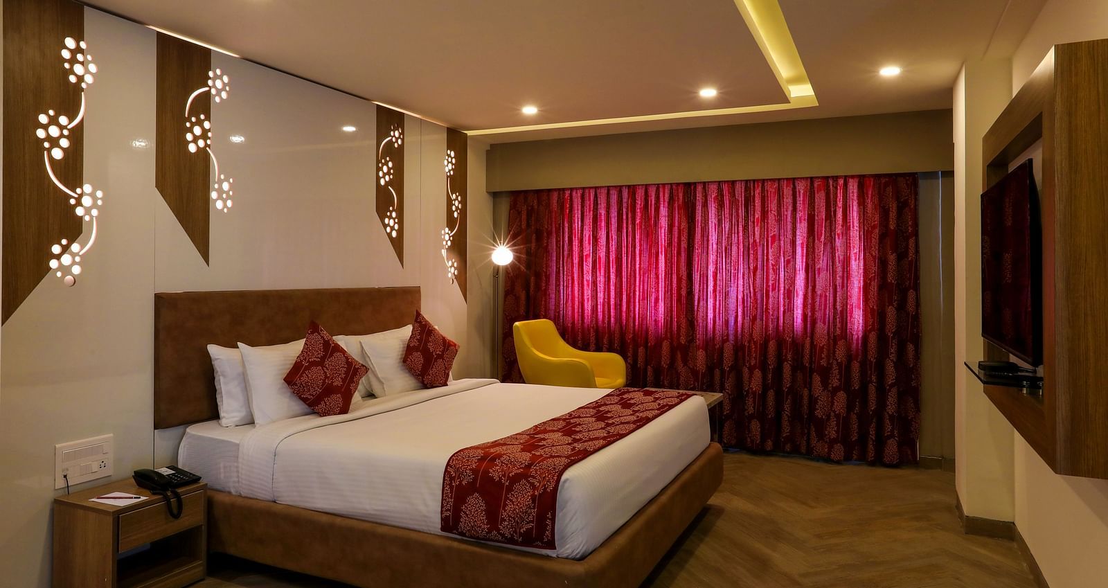 A bedroom with a large bed placed in the middle facing a mounted television - Mango Hill Central, Chennai