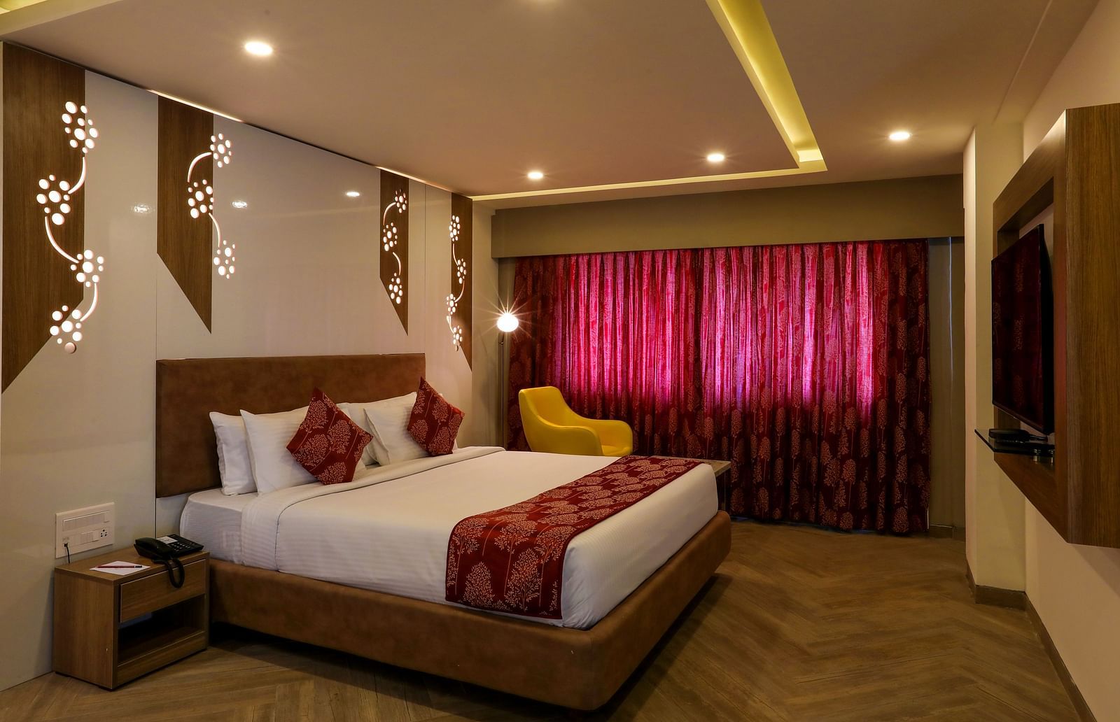 A bedroom with a large bed placed in the middle facing a mounted television - Mango Hill Central, Chennai