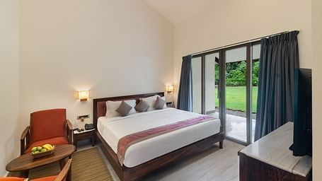 image of the luxury suite villa at aranya vilas featuring a comfortable king size bed with three cushions well kept on it with huge french windows besides it