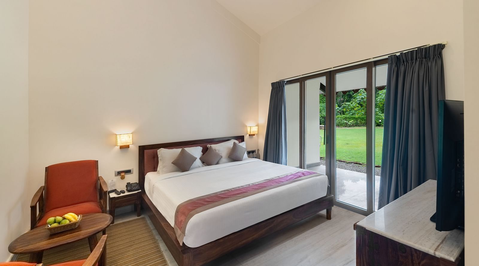 image of the luxury suite villa at aranya vilas featuring a comfortable king size bed with three cushions well kept on it with huge french windows besides it