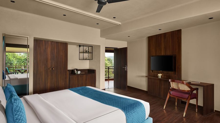 Super Deluxe Room with Balcony featuring a large bed with a blue and white colour scheme, a flat-screen TV, and a desk at DGV Resort by Treat, Silvassa