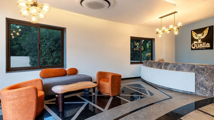 The Qualia Resort Club & Brewery, Udaipur featuring a modern lounge with a orange armchairs and a counter, designed with contemporary lighting and decor.