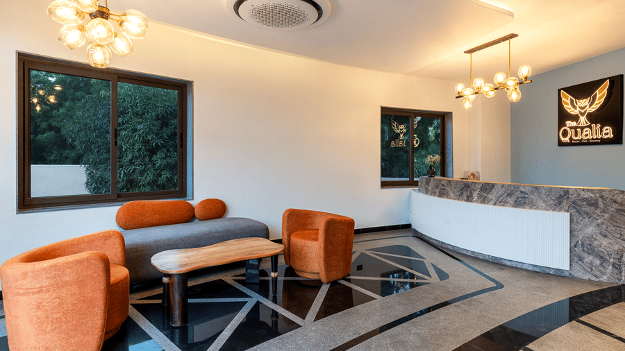 The Qualia Resort Club & Brewery, Udaipur featuring a modern lounge with a orange armchairs and a counter, designed with contemporary lighting and decor.