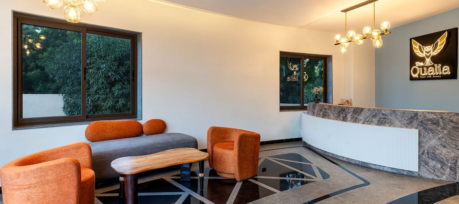 The Qualia Resort Club & Brewery, Udaipur featuring a modern lounge with a orange armchairs and a counter, designed with contemporary lighting and decor.