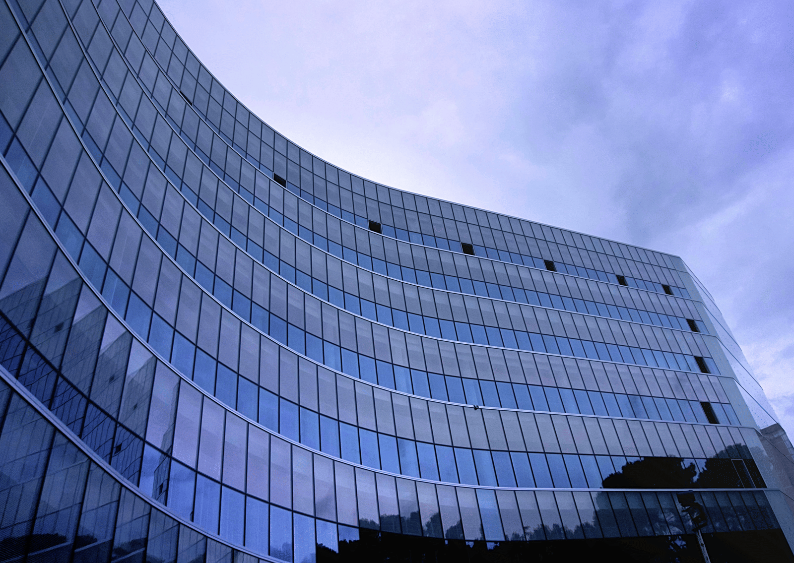 Curved glass office building reflecting the sky with modern architecture and multiple floors
