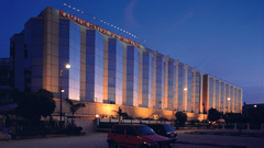 Facade view during twilight with the lights on and signage lit - Hotel Ramada Plaza Palm Groveduring twilight with the lights on and signage lit - Hotel Ramada Plaza Palm Grove