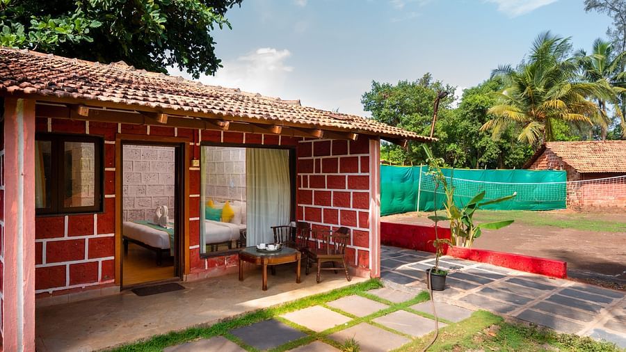 Lotus Eco Beach Resort Murud - exterior view of the Konkan cottage with a small outdoor badminton court in the background