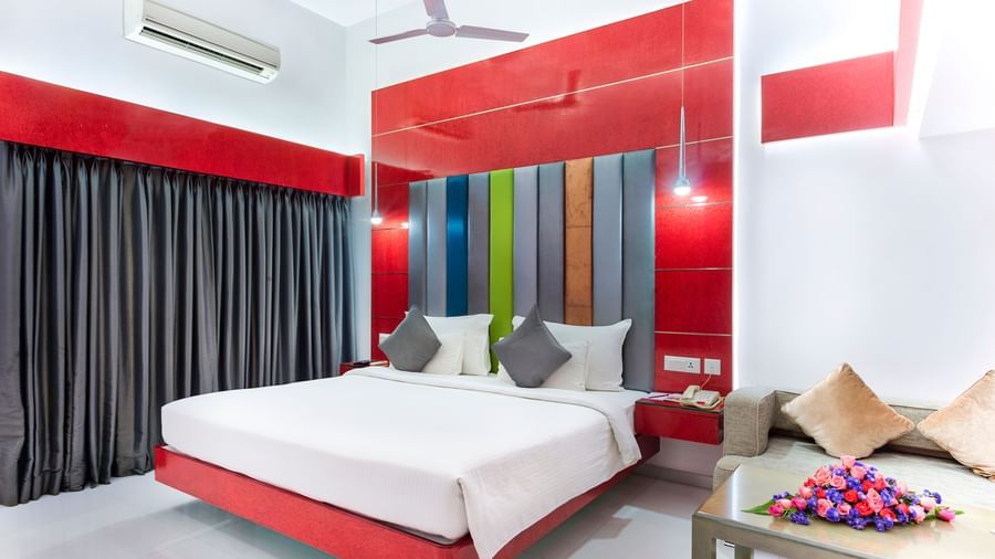 A room with a king size bed featuring colourful wall accents, grey curtains and red & white decor at Grande Bay Resort & Spa.