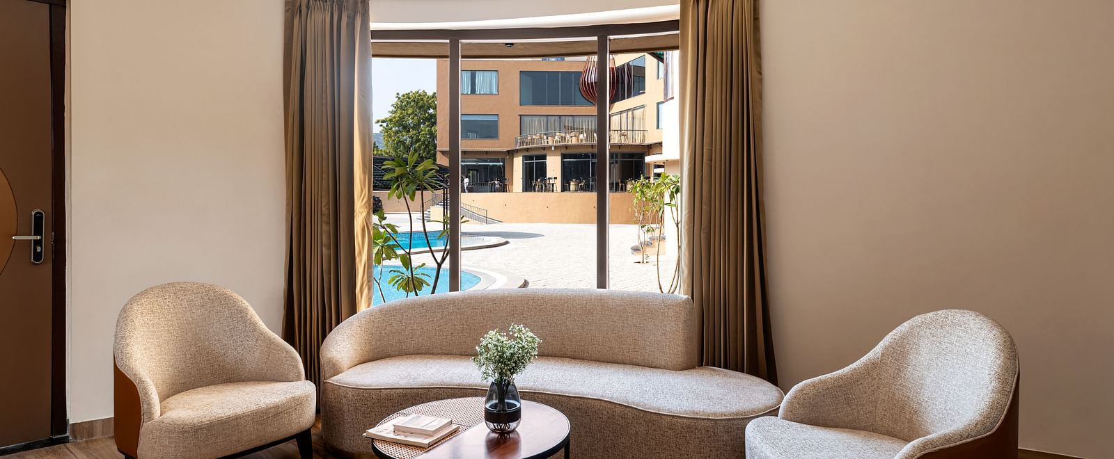 Luxury Villa with Plunge Pool showcases a seating area with armchairs and a coffee table, with a window view of the outdoors at The Qualia Resort Club & Brewery, Udaipur.