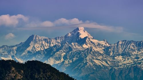 A Far view of snow capped mountains with clouds behind it.