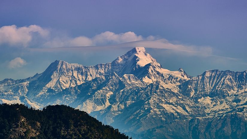 Distant view of snow capped mountains with clouds behind it