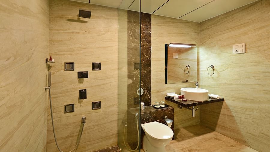 A hotel bathroom with a walk-in shower, toilet, and sink.