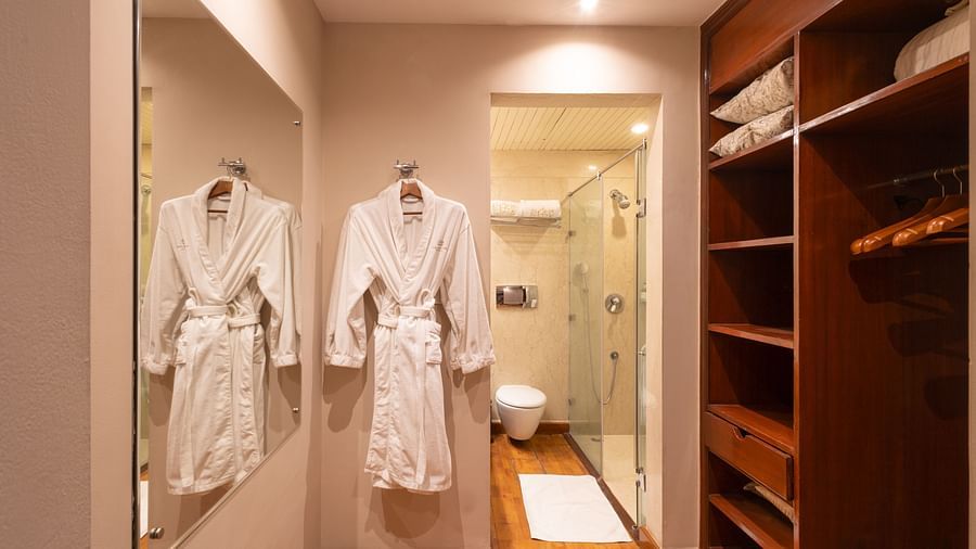 image of a walk in closet with a bathrobe hanging in the frame and medium sized mirror at our regent suites in new delhi at the Claridges