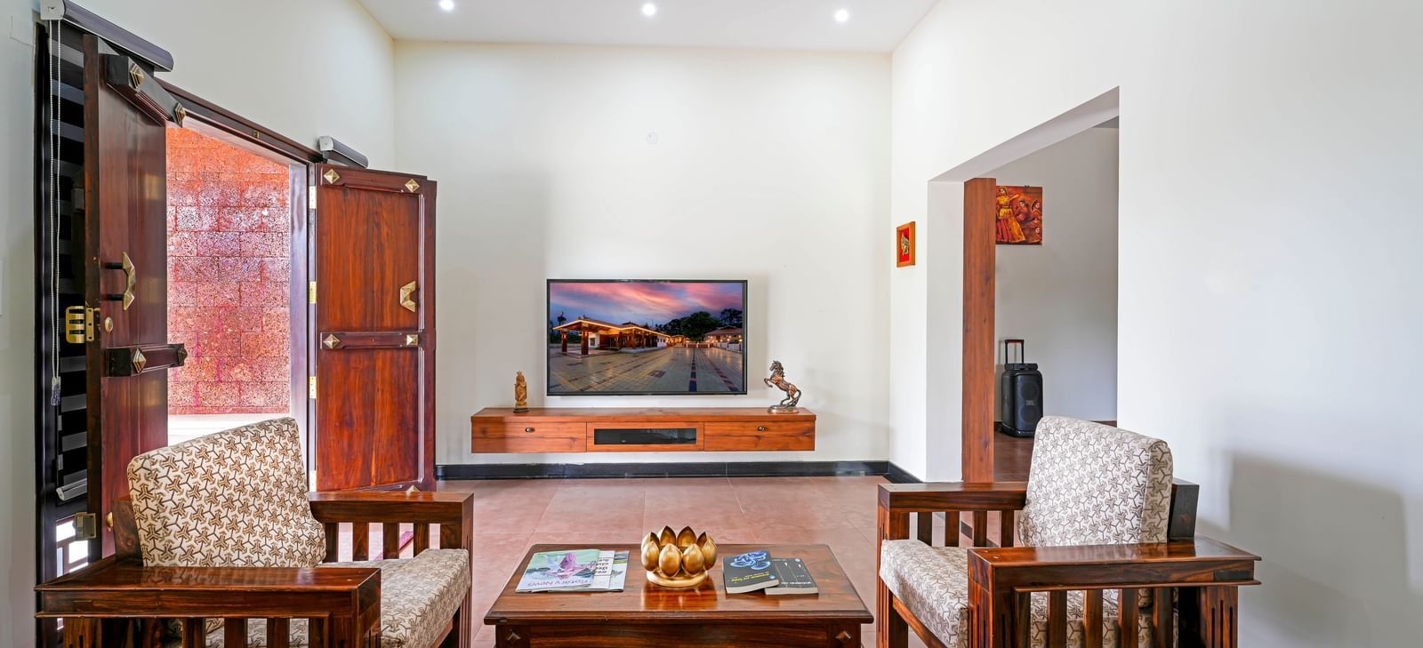 A cozy living area in the villa at Bhuthanakadu Retreat, showcasing a comfortable sofa, a wooden coffee table, and a TV with a stand, all with warm lighting.