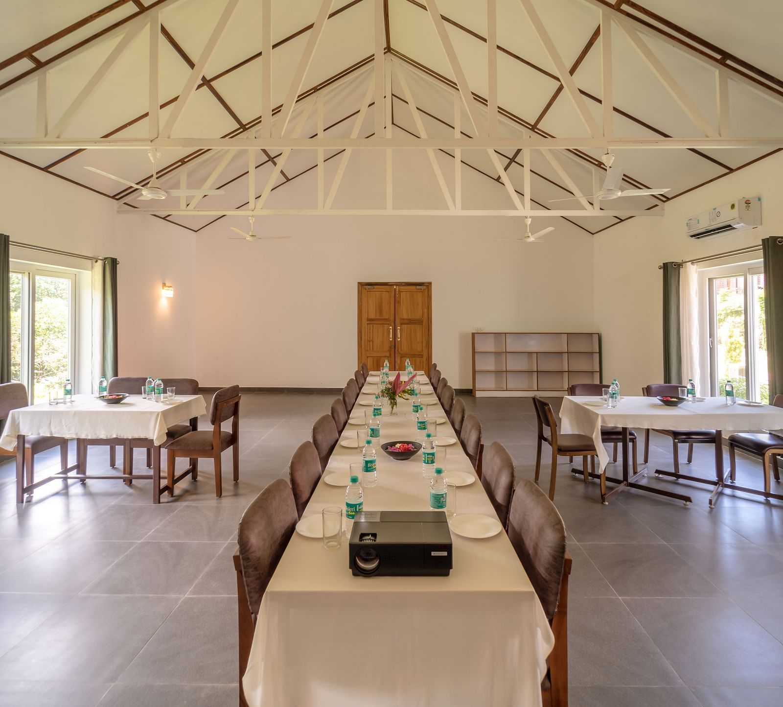 a large dining table in the centre with other small tables on the side inside a room - Neer Ganga Resorts