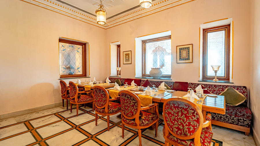 A corner shot of the Marble Arch restaurant at Noor-Us-Sabah Palace, Bhopal, with ample of natural light coming from the square-shaped window over the dining tables.