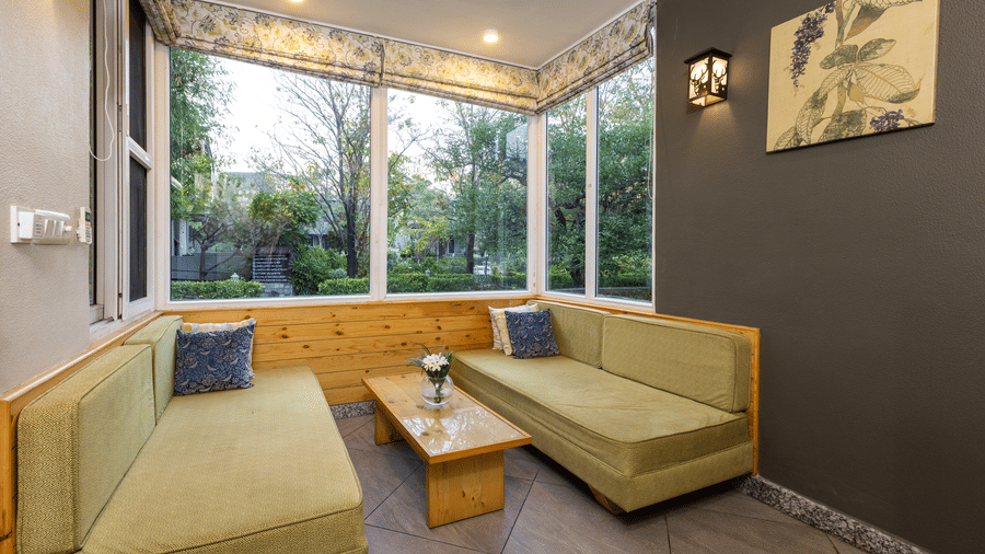 Villa living area with a large sectional sofa and a view of the outdoors through a window at The Golden Tusk, Jim Corbett