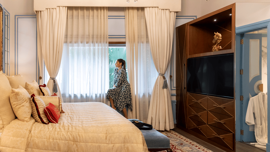 image of a woman gancing outside the window of the willigdon crescent suite admiring the view outside - The Claridges New Delhi
