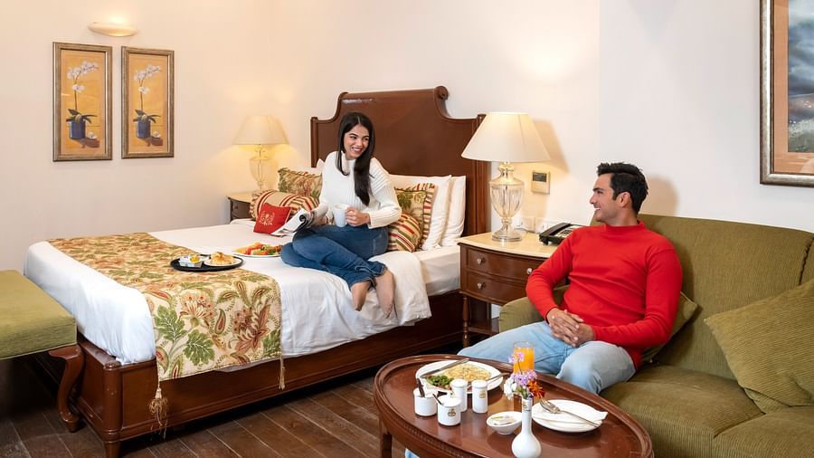 image of a couple sitting on the bed and the sofa in our Duplex Family Suite