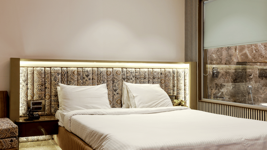 Room with crisp white bedding, a large padded headboard, and indirect backlighting on the wall at Kumar Resort by Turtle.