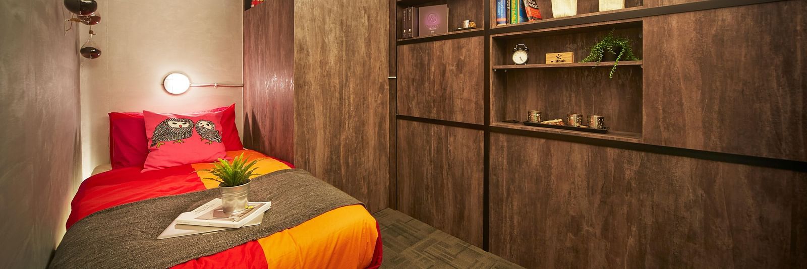 A cosy bedroom with wooden interiors featuring a single bed in the corner.