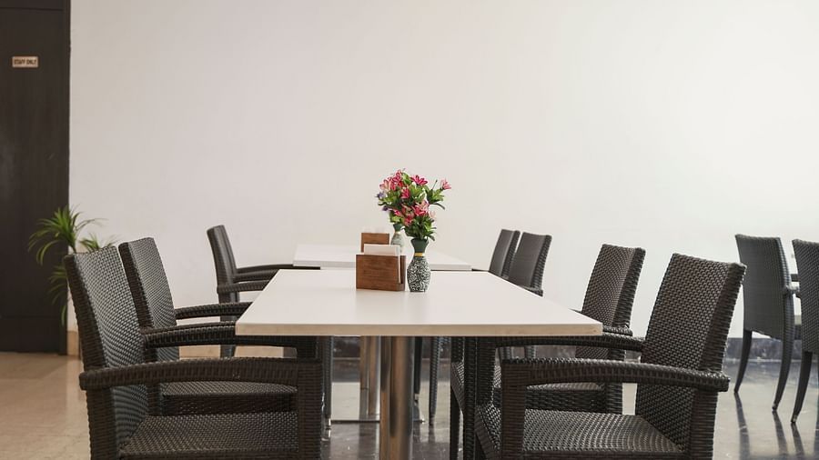 A spacious dining area at BNGV Grandeur Hotel and Banquets,set with dark tables and chairs, and a large floral centerpiece on one of the tables.