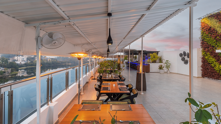 A wide angle shot of the seating area of the rooftop restaurant in Udaipur with a view of the lake and sky - Hotel Rajdarshan, Udaipur.