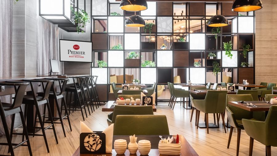 Dining area at Best Western Premier Westlands with arranged tables, chairs, and decorative wall panels.