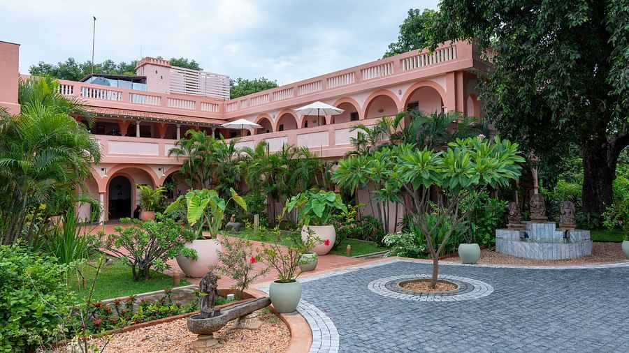 Pathway of a resort with a tree in the middle of it and a backdrop of sky with clouds.