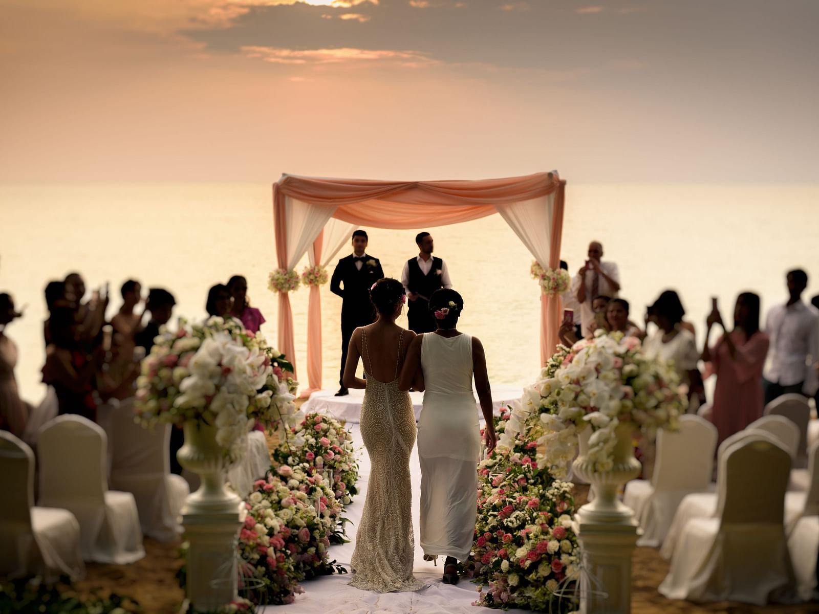 The bride accompanied by her mother walking down the aisle during the evening - Maikhao Dream Villa Resort & Spa, Phuket