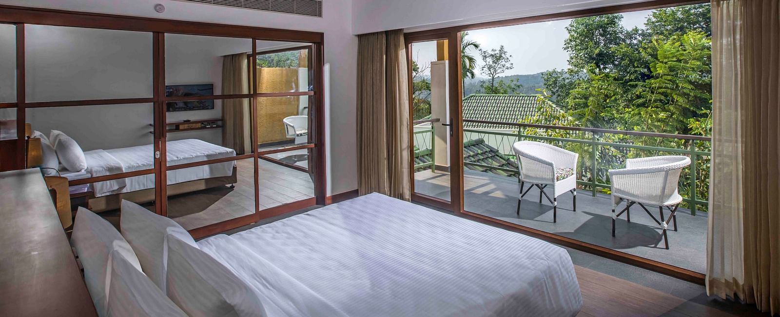 Image of the bed at the villa of our hotel with expansive glass window | Great Trails Wayanad by  GRT hotels.