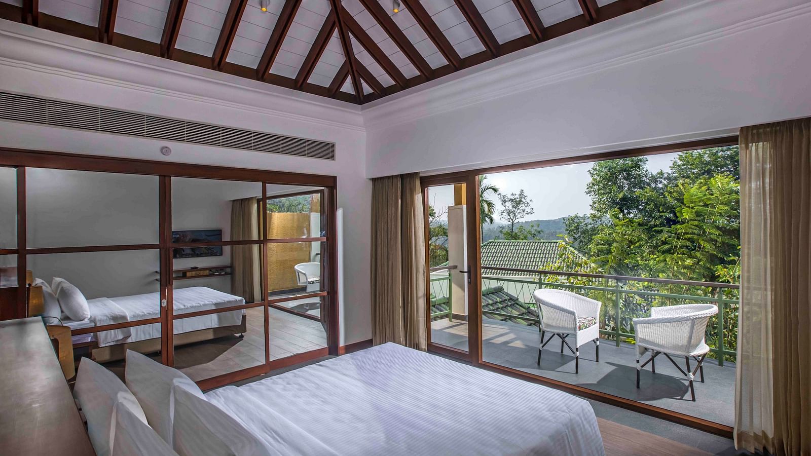 Image of the bed at the villa of our hotel with expansive glass window | Great Trails Wayanad by  GRT hotels.