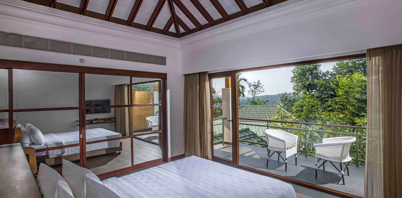 Image of the bed at the villa of our hotel with expansive glass window | Great Trails Wayanad by  GRT hotels.
